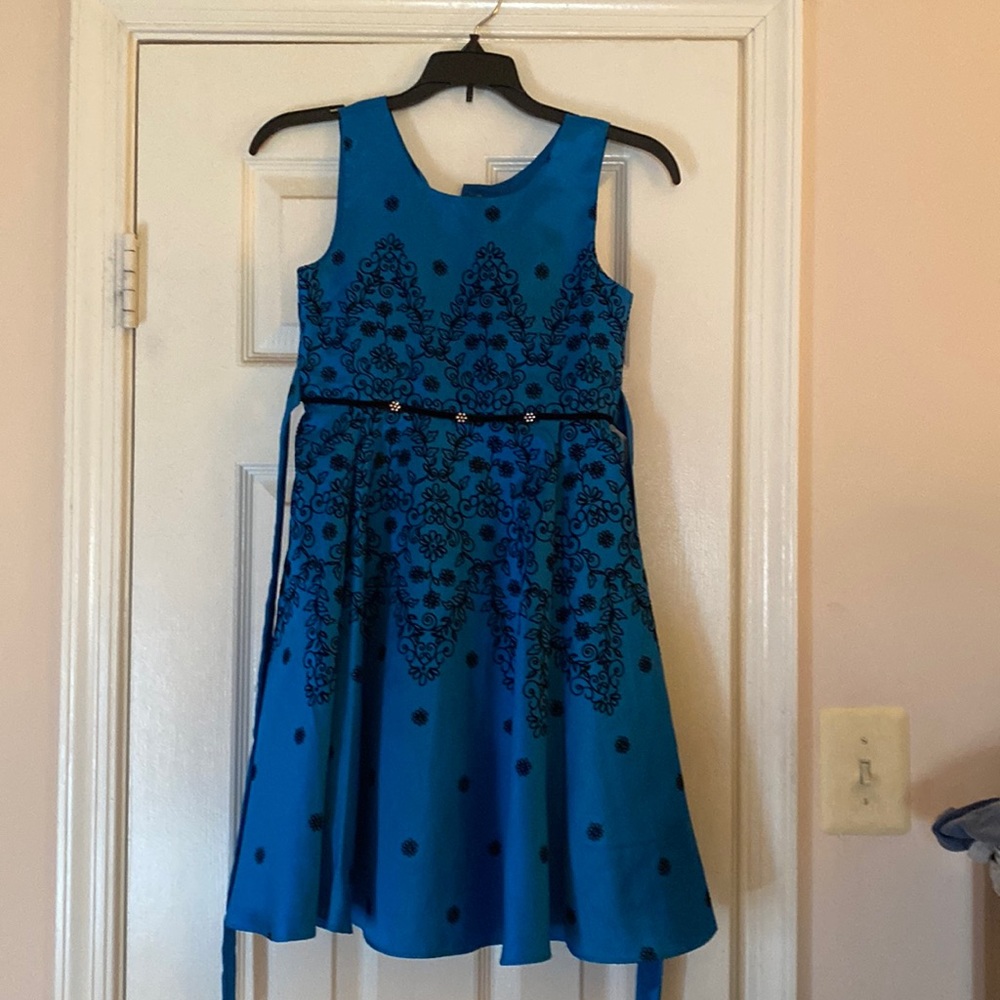A beautiful blue dress with black top stitching of flowers. Ties in the back.